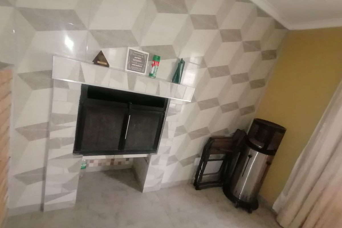 A living room area featuring a built-in fireplace with a geometric tiled surround and tiled flooring.
