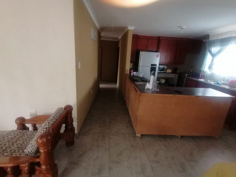 Open plan living and kitchen area featuring tiled flooring, built-in cabinetry, and a kitchen island, requiring some cosmetic updates to the finishes.