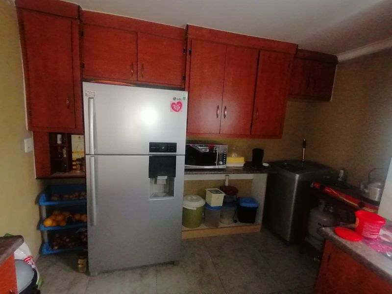A functional kitchen area featuring built-in wooden cabinetry and tiled flooring, offering a practical layout for daily food preparation and storage.