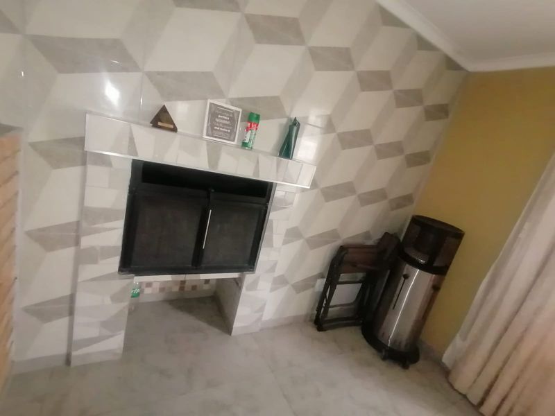 A living room area featuring a built-in fireplace with a geometric tiled surround and tiled flooring.