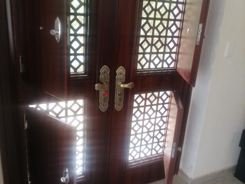 A secure double entry door featuring decorative metal grilles and tiled flooring in the entrance area.