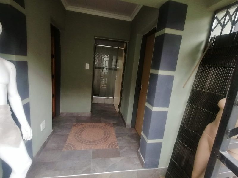 A tiled hallway featuring decorative pillars and access to multiple internal rooms, providing a functional transition space within the home.