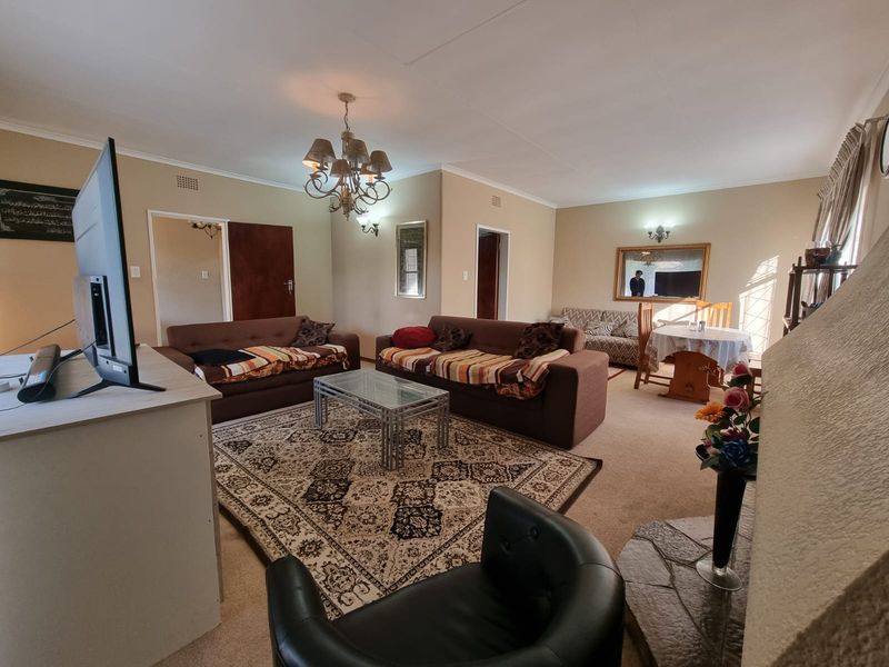Spacious living room featuring a stone hearth, coved ceilings, and classic lighting fixtures, offering a comfortable and traditional layout.