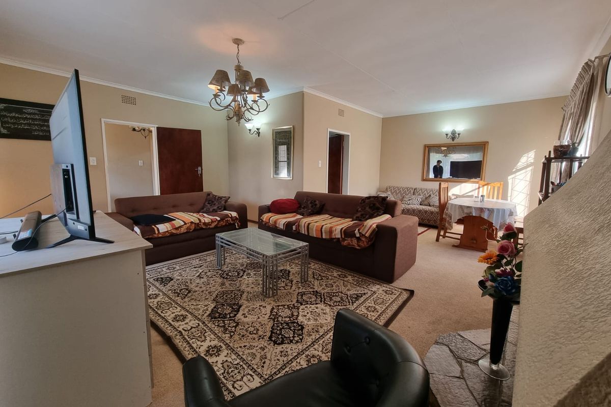 Spacious living room featuring a stone hearth, coved ceilings, and classic lighting fixtures, offering a comfortable and traditional layout.