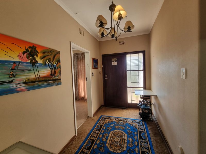 A functional entrance hall featuring a classic chandelier, timber front door with sidelight, and neutral wall finishes.
