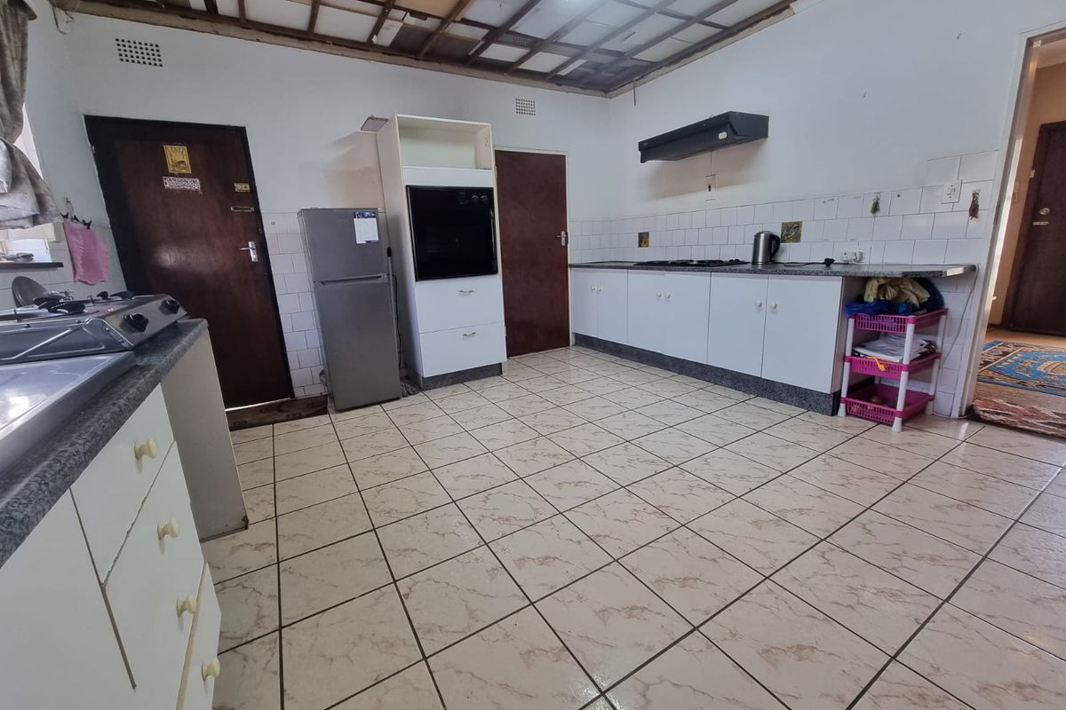 A kitchen featuring tiled flooring, built-in cabinetry, and an oven, currently requiring ceiling repairs and general renovation to improve the space.