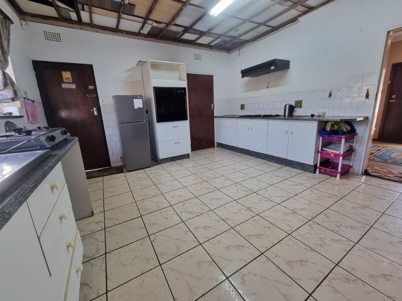 A kitchen featuring tiled flooring, built-in cabinetry, and an oven, currently requiring ceiling repairs and general renovation to improve the space.