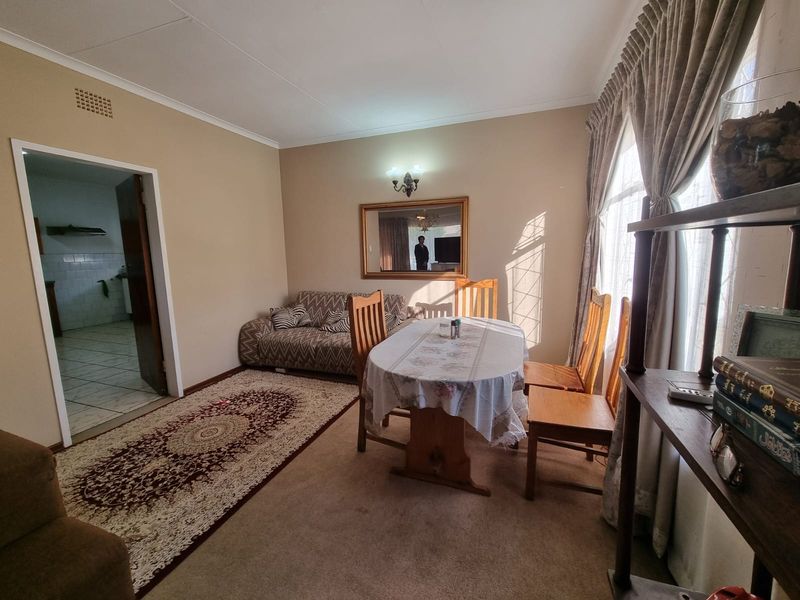 A dining room featuring neutral wall tones, coved ceilings, and direct access to the kitchen area.