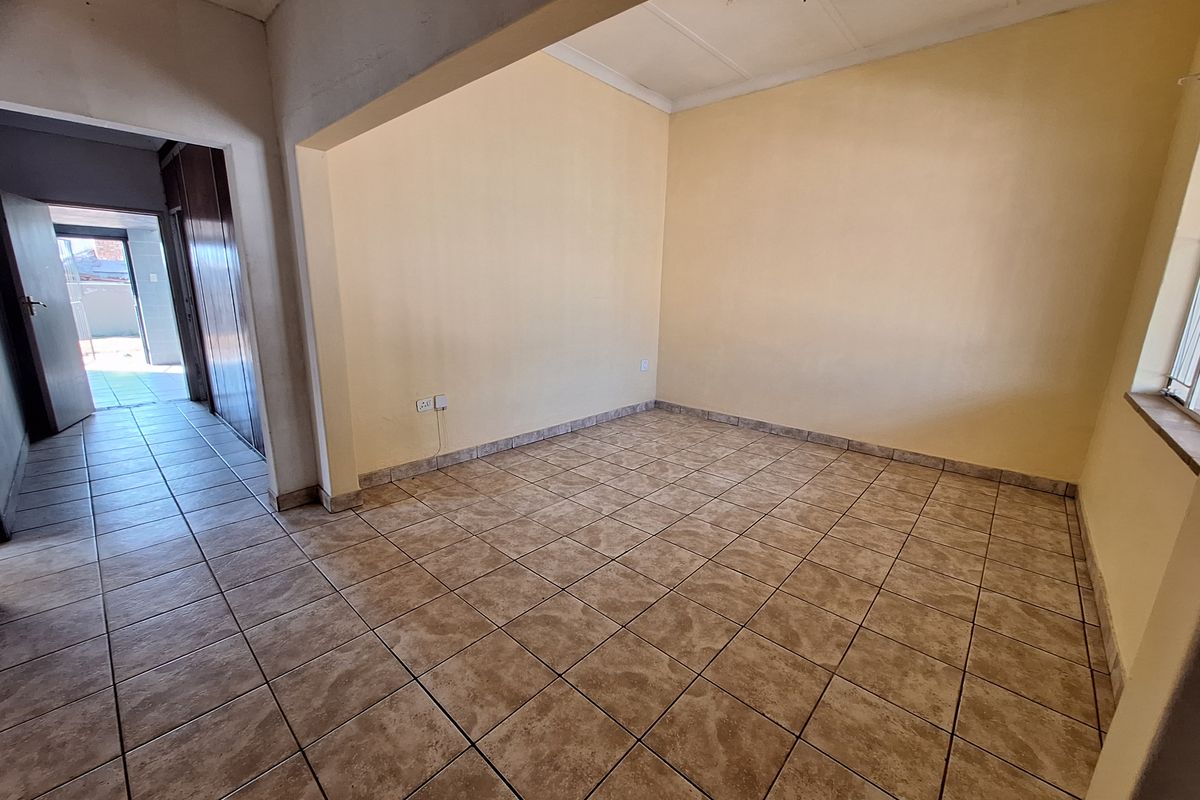 An empty living room featuring neutral ceramic floor tiles and light-colored walls, providing a blank canvas for interior design and personalization.