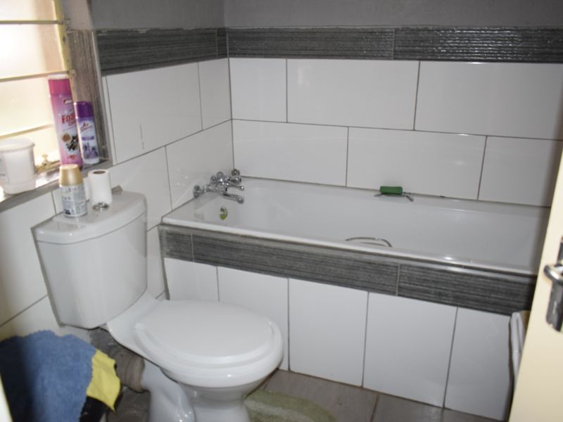 A functional bathroom featuring a standard bathtub, toilet, and tiled wall finishes.