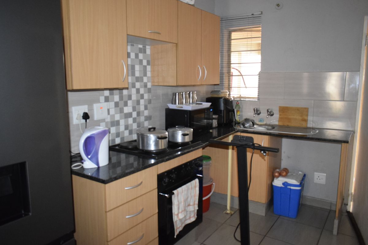 Compact kitchen featuring laminate cabinetry, granite countertops, mosaic tile backsplash, built-in oven, and electric hob with tiled flooring.