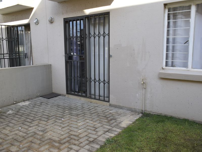 A paved patio area featuring security gates and bars, providing direct access to the townhouse interior with an external water tap.