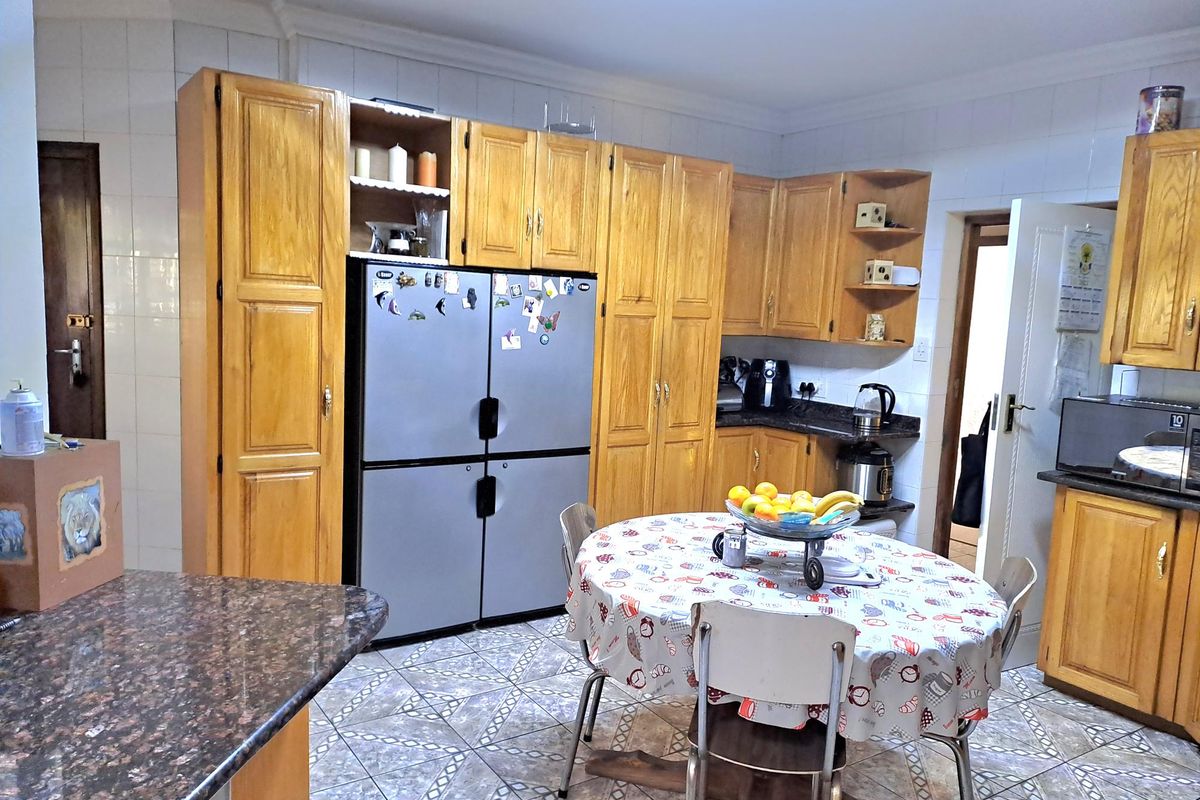 A functional kitchen featuring traditional wooden cabinetry, granite countertops, and tiled flooring, offering a classic layout with ample storage space.