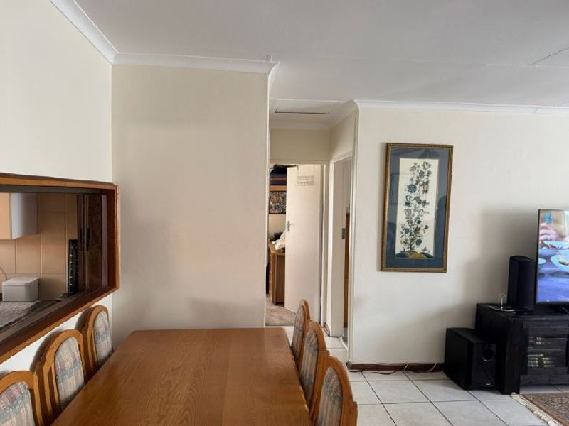 Open plan living and dining area featuring tiled flooring, coved cornicing, and a convenient kitchen serving hatch connecting to the adjacent space.