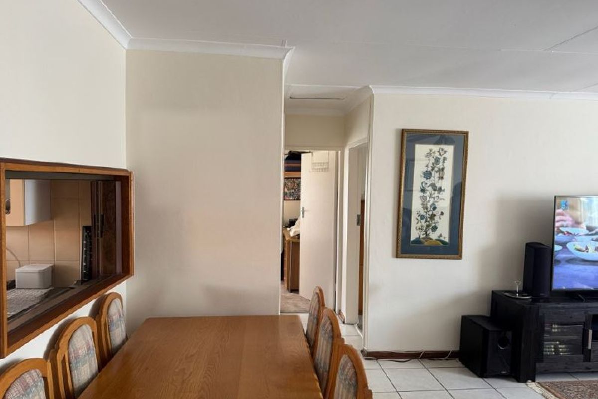 Open plan living and dining area featuring tiled flooring, coved cornicing, and a convenient kitchen serving hatch connecting to the adjacent space.