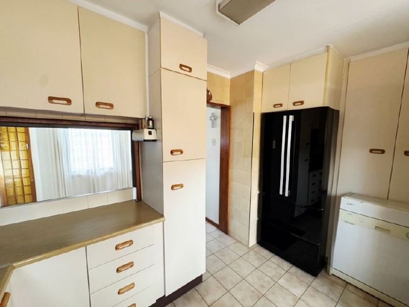 A functional kitchen featuring dated built-in cabinetry, tiled flooring, and a tiled backsplash, offering potential for a modern renovation.