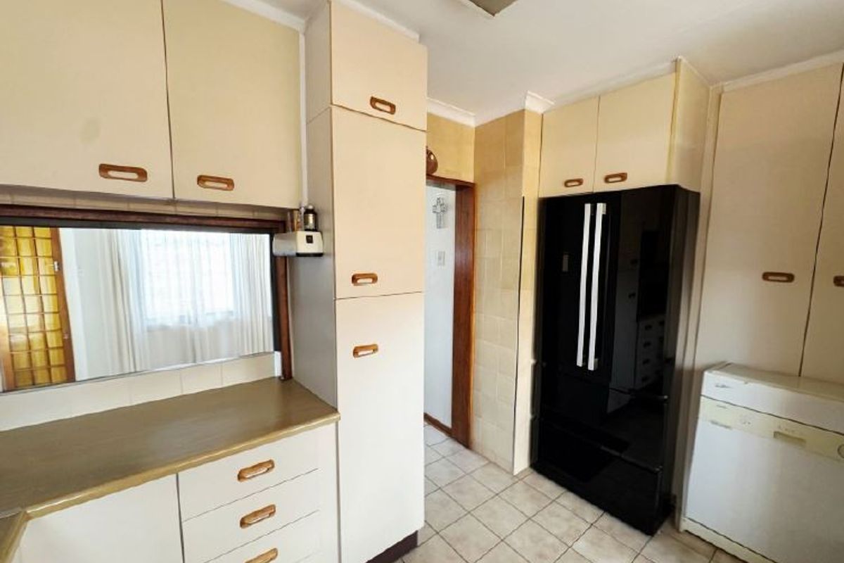 A functional kitchen featuring dated built-in cabinetry, tiled flooring, and a tiled backsplash, offering potential for a modern renovation.