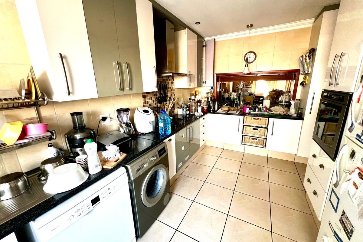A functional kitchen featuring two-tone cabinetry, tiled flooring, a built-in oven, and an extractor fan, offering ample storage and workspace.
