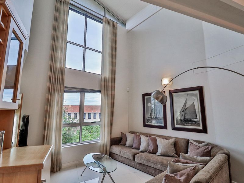 Spacious living area featuring double-volume ceilings, large windows providing ample natural light, and built-in cabinetry.