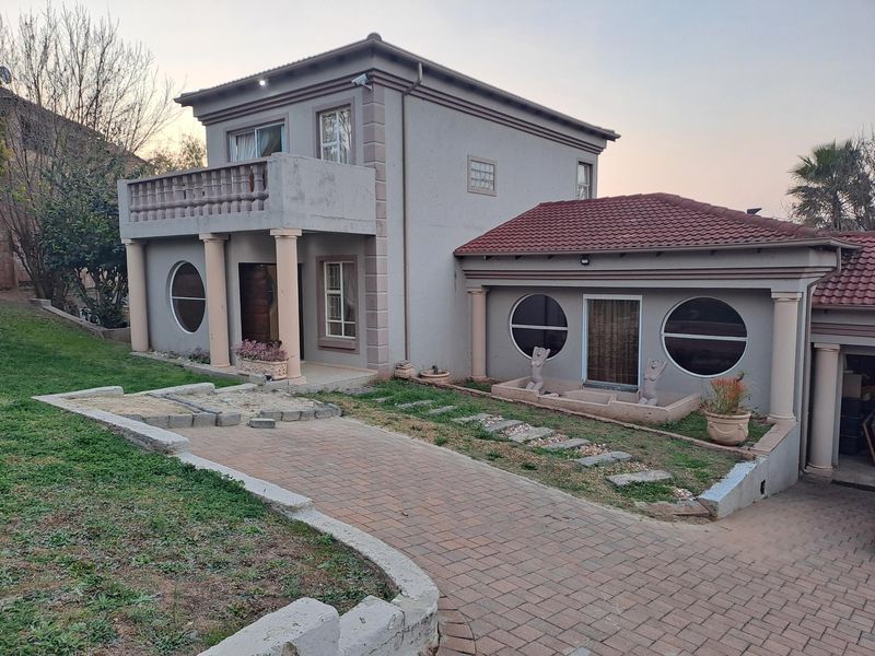 Front elevation of a two-story house featuring a paved driveway, balcony with concrete columns, and distinctive circular windows.