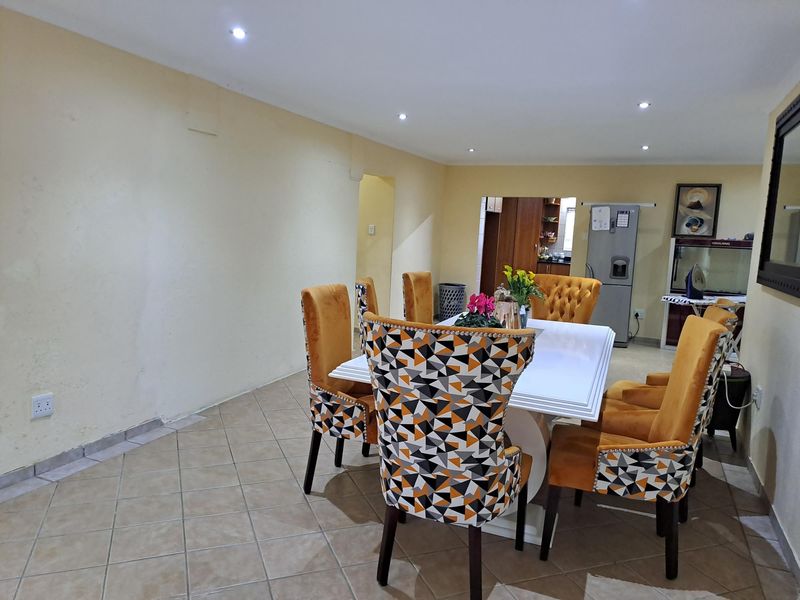 A dining area featuring ceramic floor tiles and recessed downlighting, providing a functional space adjacent to the kitchen area.