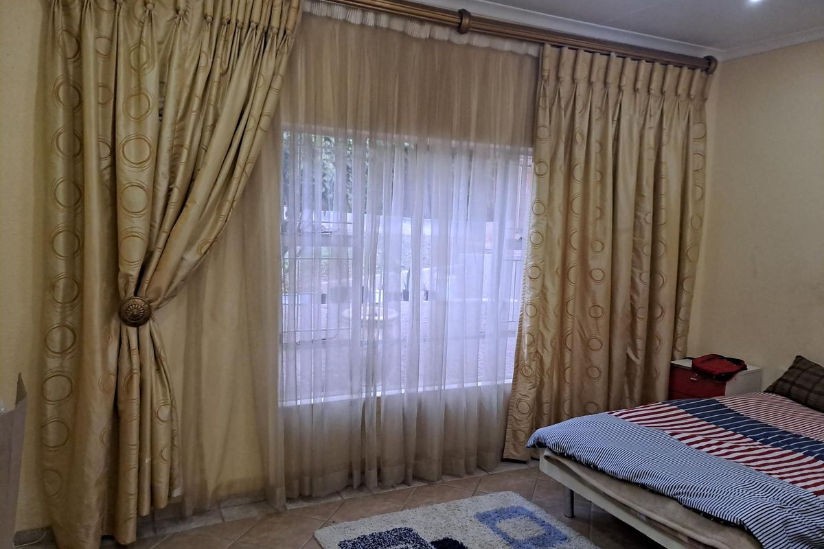 A bedroom featuring tiled flooring, recessed downlights, and large window treatments with decorative curtains.