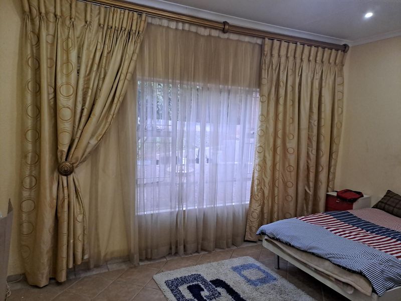 A bedroom featuring tiled flooring, recessed downlights, and large window treatments with decorative curtains.