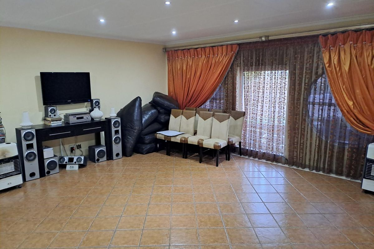 Spacious living area featuring tiled flooring, recessed downlighting, and large sliding glass doors with integrated curtain tracks.