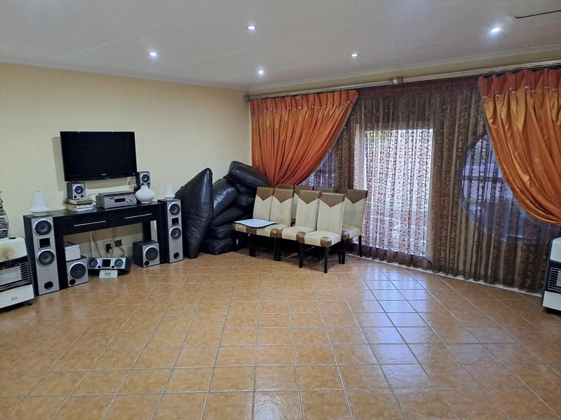 Spacious living area featuring tiled flooring, recessed downlighting, and large sliding glass doors with integrated curtain tracks.