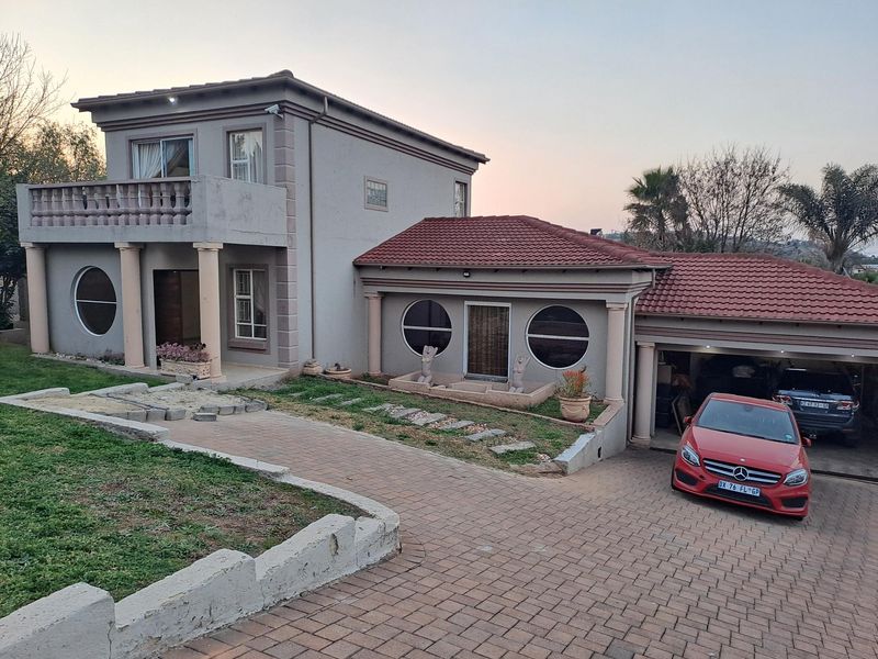 Front elevation of a double-story house featuring a paved driveway, double garage, balcony with concrete balustrade, and distinctive circular windows.