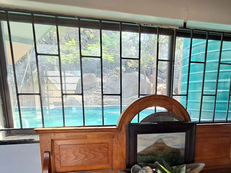Interior view looking through a window with security bars, featuring a view of the outdoor swimming pool area.