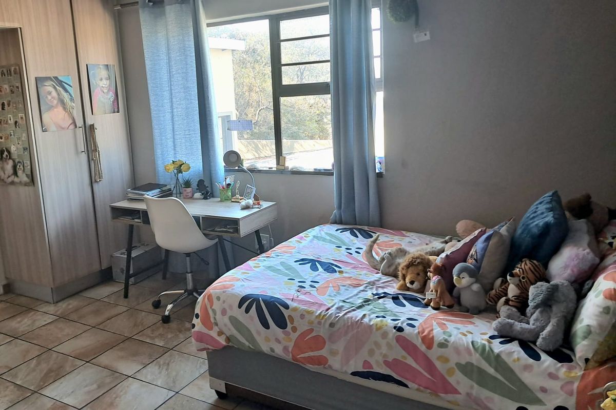 A functional bedroom featuring tiled flooring, a built-in wardrobe, and a window providing natural light.
