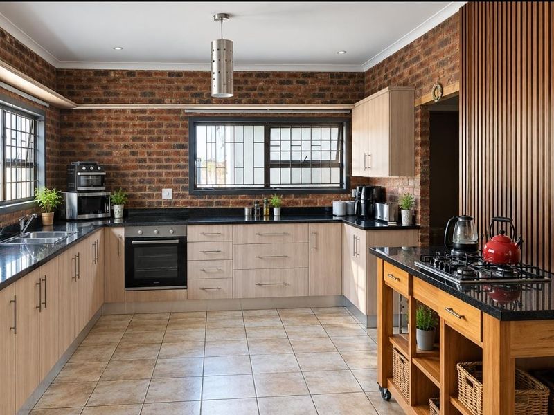 Modern kitchen featuring exposed brick walls, granite countertops, light wood cabinetry, and a timber slat feature wall with a central island gas hob.
