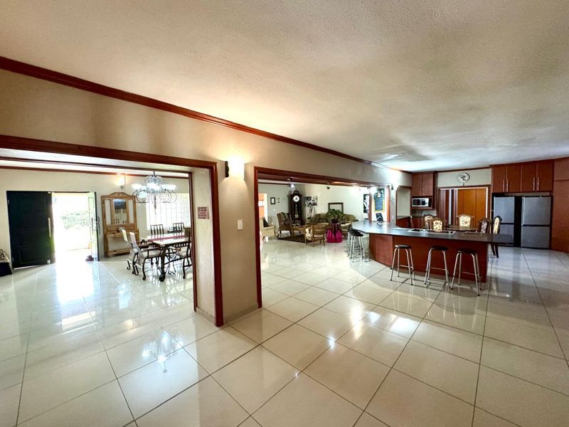 Spacious open-plan living area featuring a large kitchen with breakfast bar, dining space, and tiled flooring throughout.