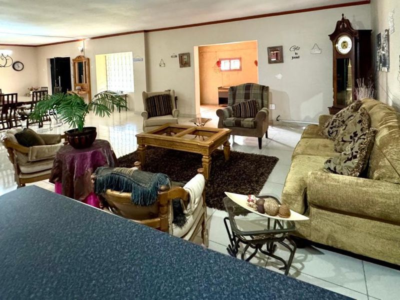 Spacious open-plan living and dining area featuring large format floor tiles and a neutral color palette, offering a versatile layout for family living.