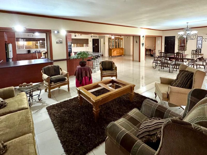 Spacious open-plan living and dining area featuring large format floor tiles, integrated kitchen cabinetry, and a seamless flow between functional zones.