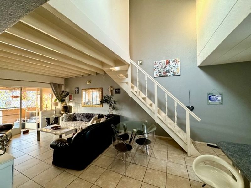 Open plan living and dining area featuring high ceilings, tiled flooring, and a central staircase leading to the upper level.