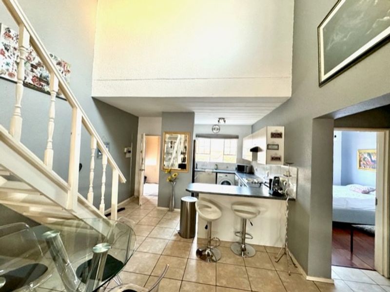 Open plan living area featuring a kitchen with breakfast bar, tiled flooring, and a staircase leading to an upper level.