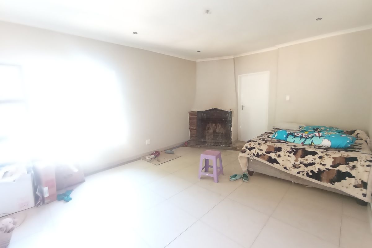A bedroom featuring tiled flooring, recessed downlights, and an unfinished fireplace area requiring cosmetic attention.