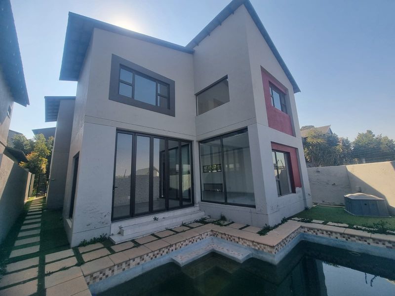 Rear exterior view of a two-story house featuring a swimming pool, tiled patio area, and large sliding glass doors.