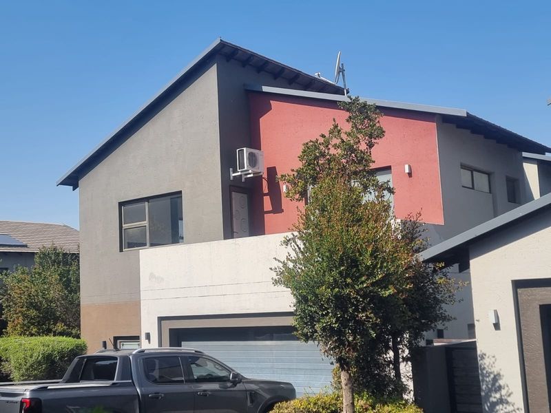 Front elevation of a modern two-story house featuring a garage, balcony, and contrasting grey and red exterior wall finishes.