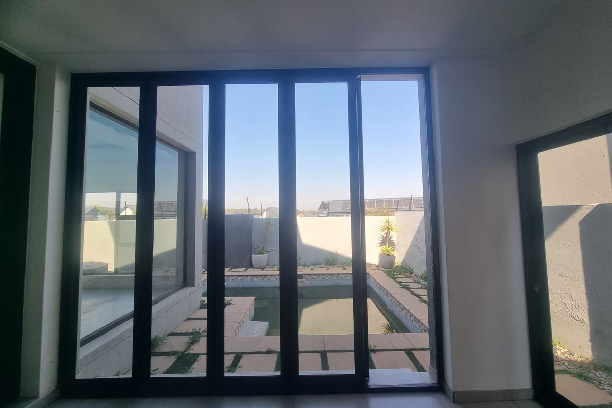 An empty living area featuring large sliding glass doors that provide a direct view and access to an outdoor swimming pool and patio area.