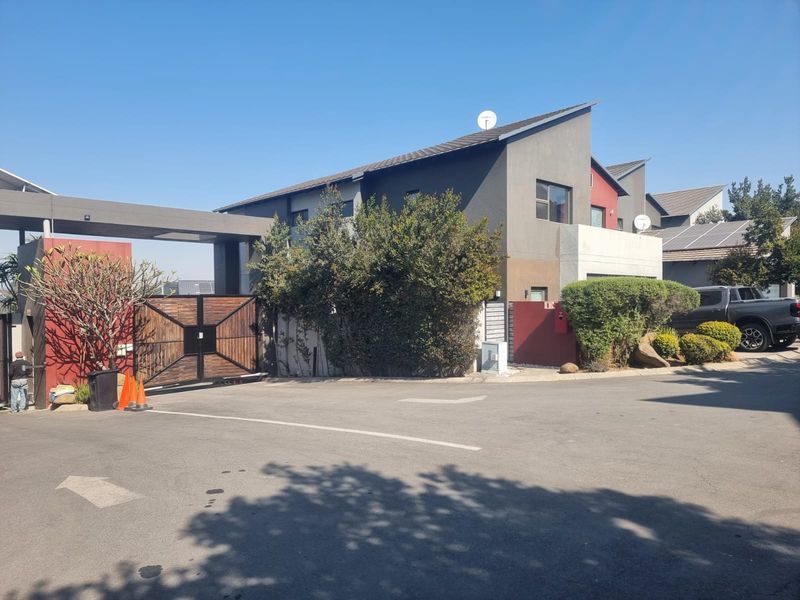 Front exterior view of a modern residential property featuring a secure gated entrance, paved driveway, and contemporary architectural design.