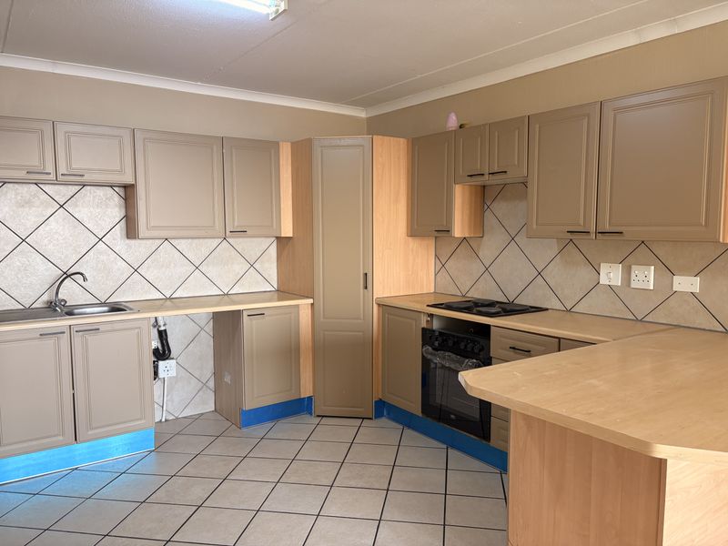 A functional kitchen featuring built-in cabinetry, laminate countertops, a breakfast bar, and tiled flooring, offering a practical layout ready for cosmetic updates.