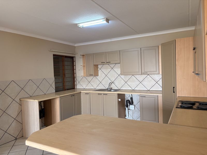 A functional kitchen featuring built-in cabinetry, laminate countertops, a stainless steel sink, and an electric hob, currently requiring minor repairs and cosmetic updates.