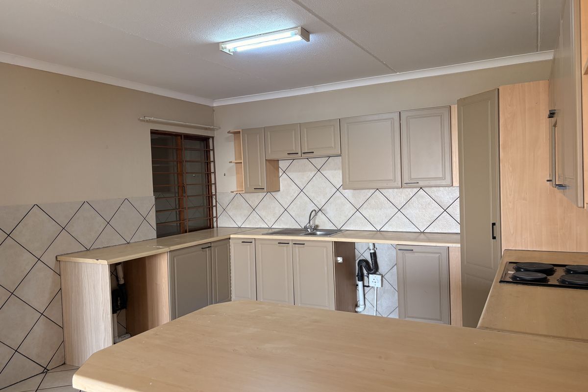 A functional kitchen featuring built-in cabinetry, laminate countertops, a stainless steel sink, and an electric hob, currently requiring minor repairs and cosmetic updates.
