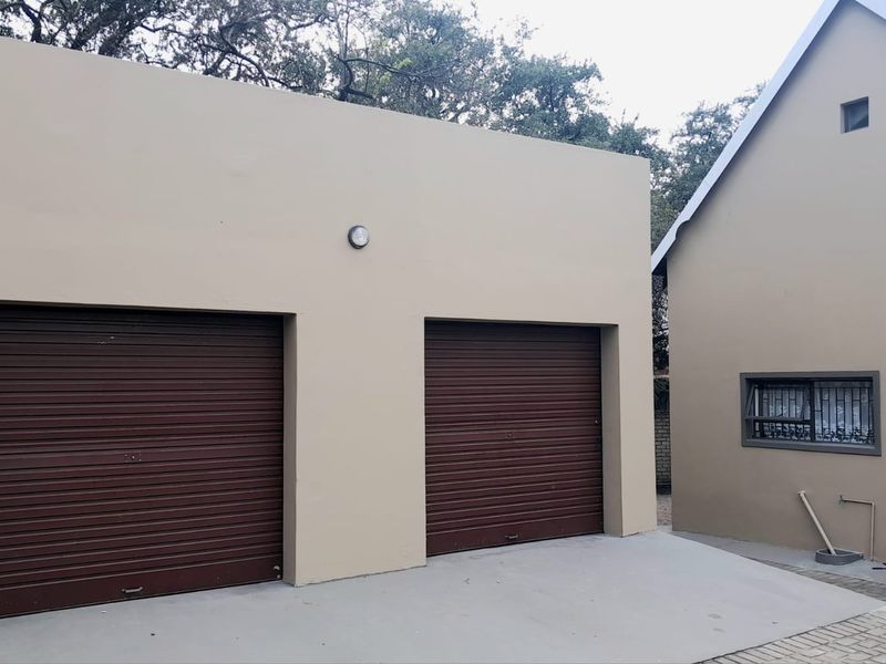 A well-maintained double garage with brown roller doors and a concrete driveway, featuring a clean exterior finish and secure window detailing.