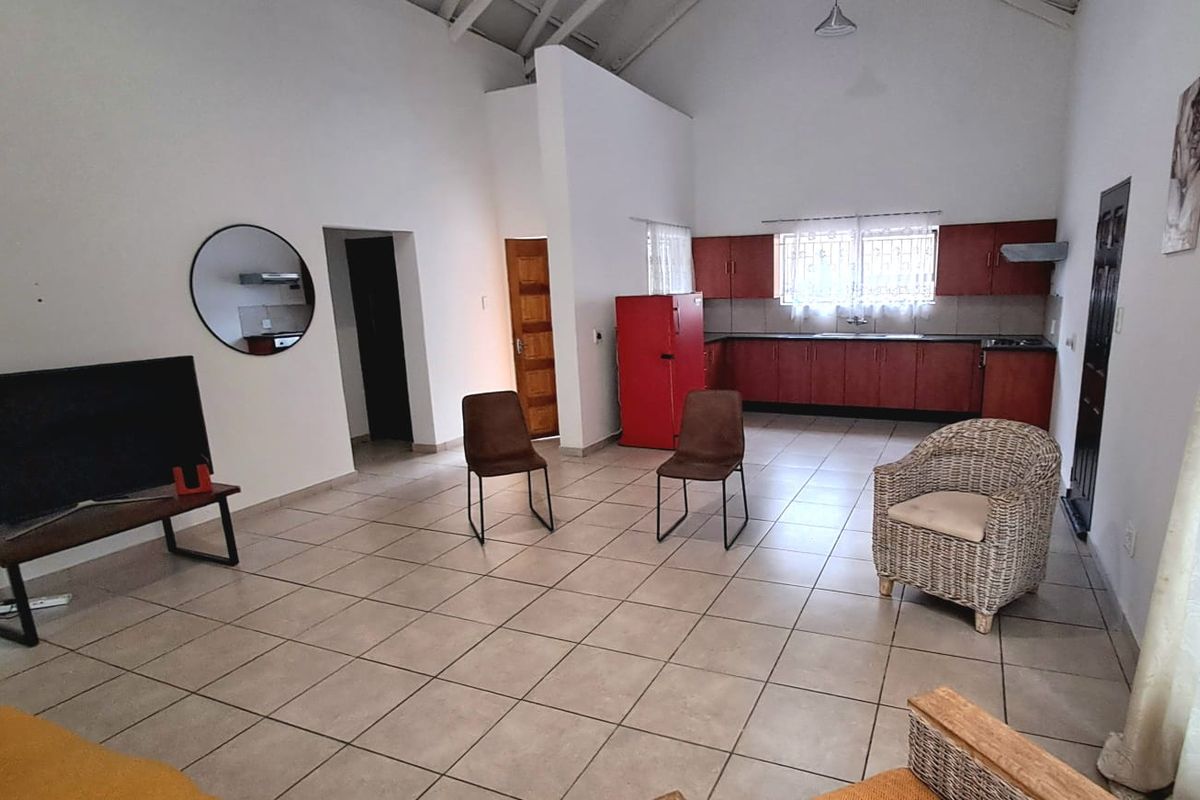 Spacious open-plan living and kitchen area featuring vaulted ceilings, tiled flooring, and functional kitchen cabinetry with integrated appliances.