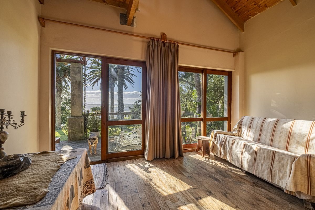A bright living room featuring exposed timber ceiling beams, warm timber flooring, and large sliding glass doors that provide direct access to the outdoor patio.