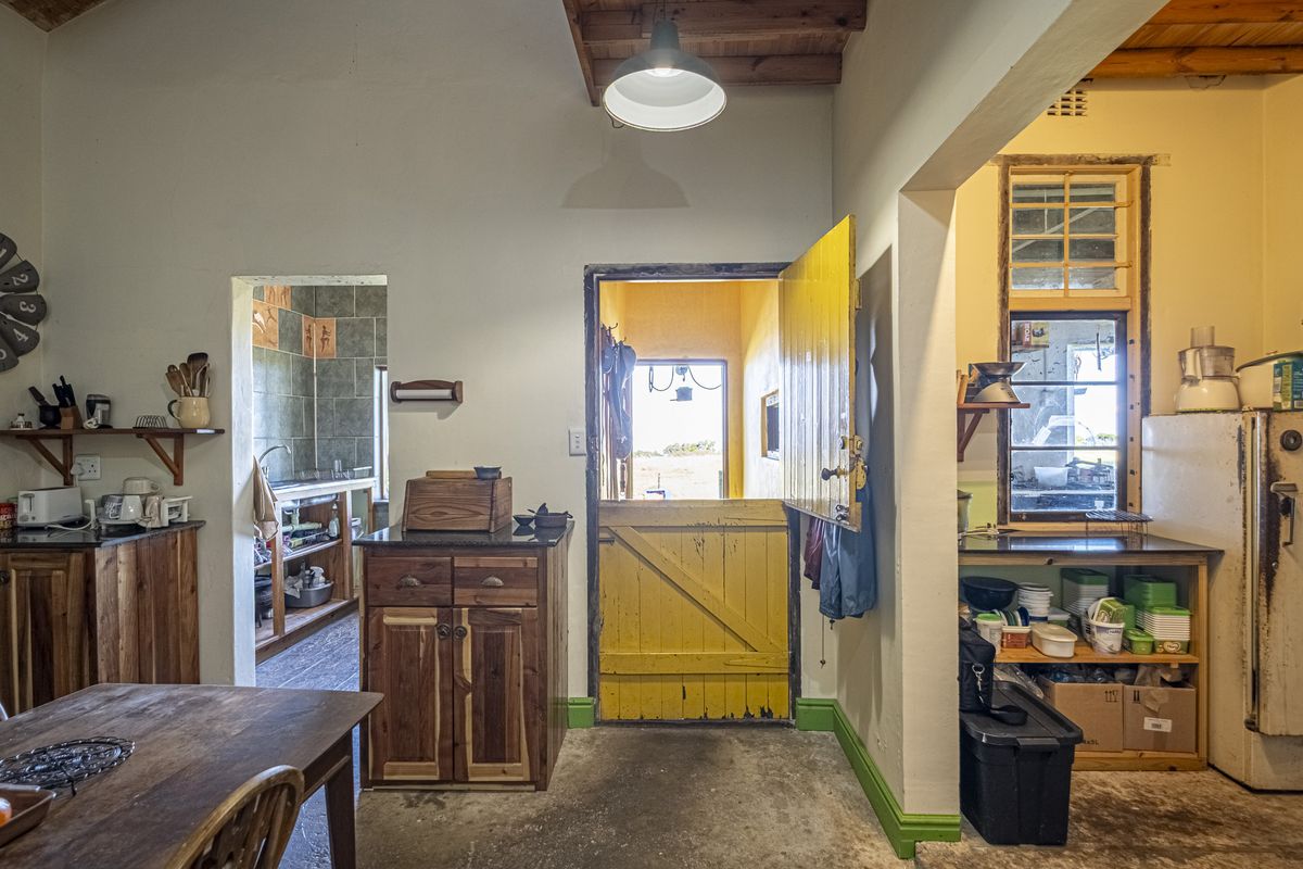 Rustic kitchen featuring exposed timber beams, wooden cabinetry with granite countertops, and a distinctive yellow stable door leading to the exterior.